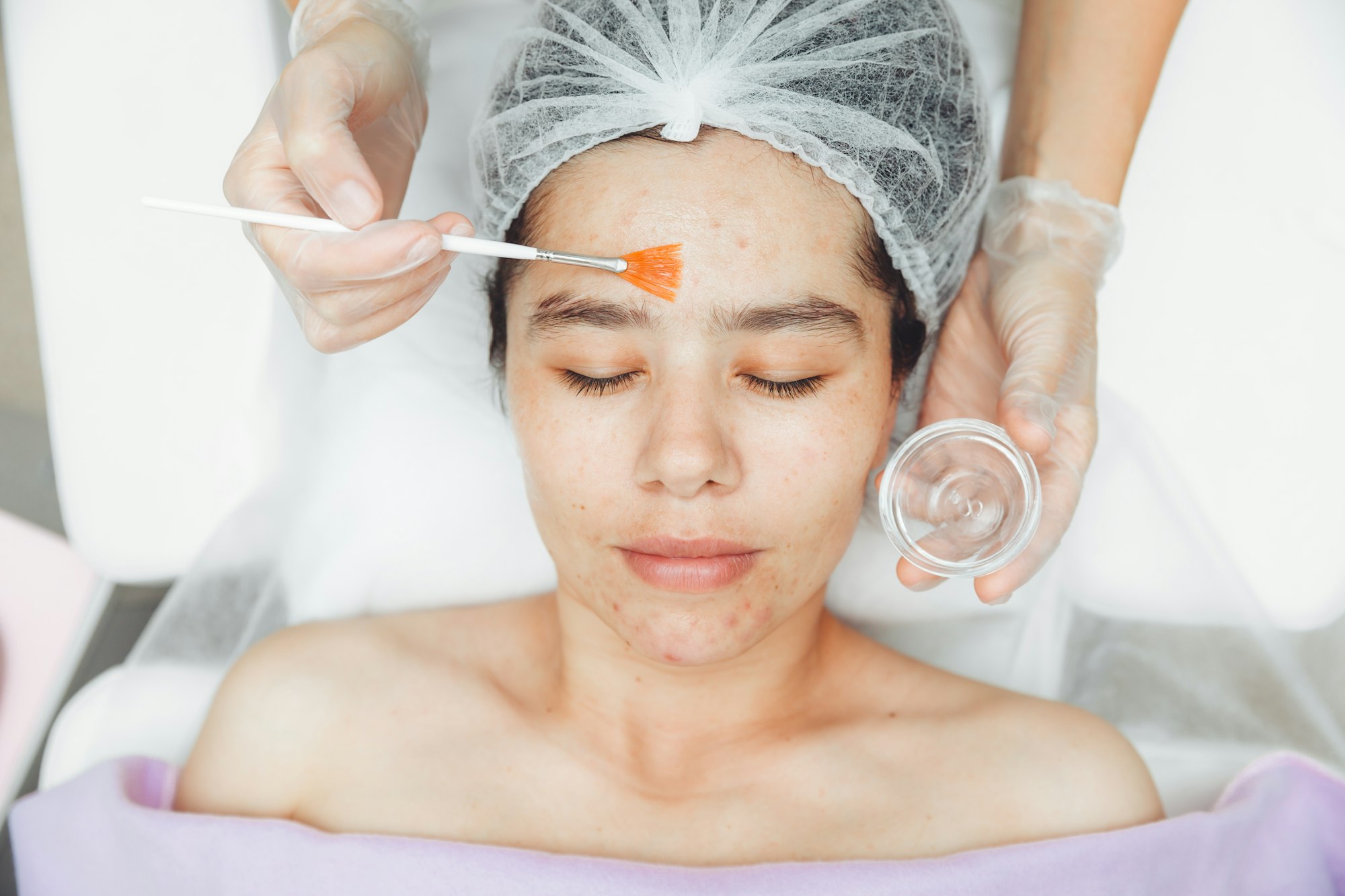 A cosmetologist does facial care and apply a face mask. cleansing a heavily soiled face.