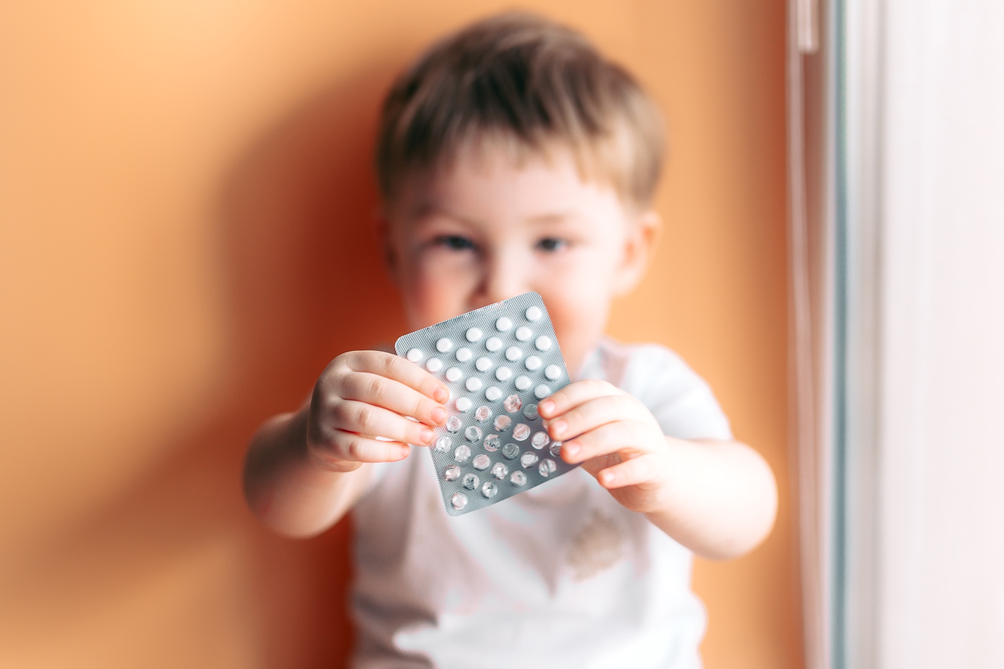 A small child toddler baby boy holds a plate with pills in his hands selected focus on pills kid