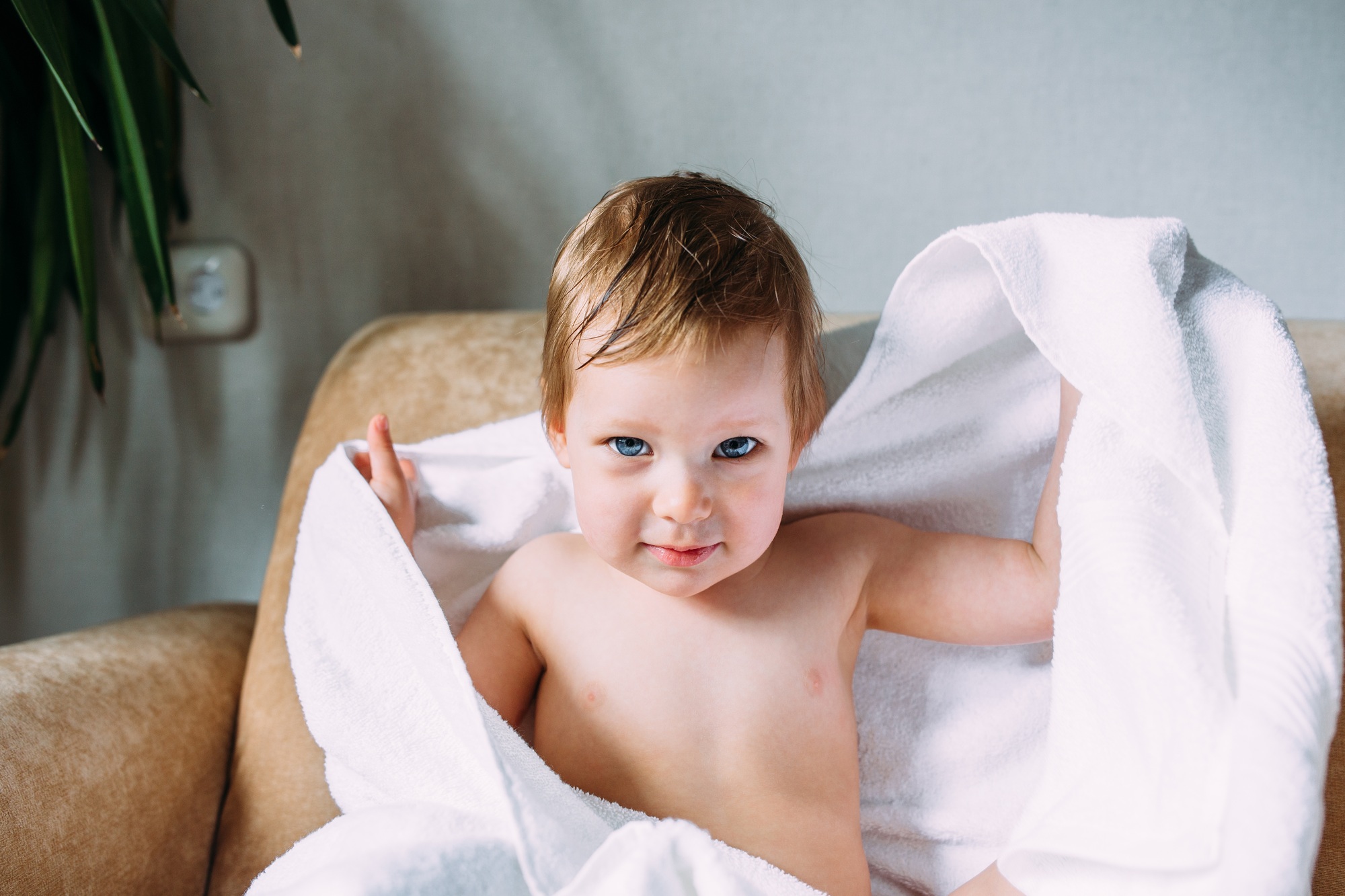 Cute child with blue eyes wrapped in a white towel. Clean baby after bath, taking care of children.