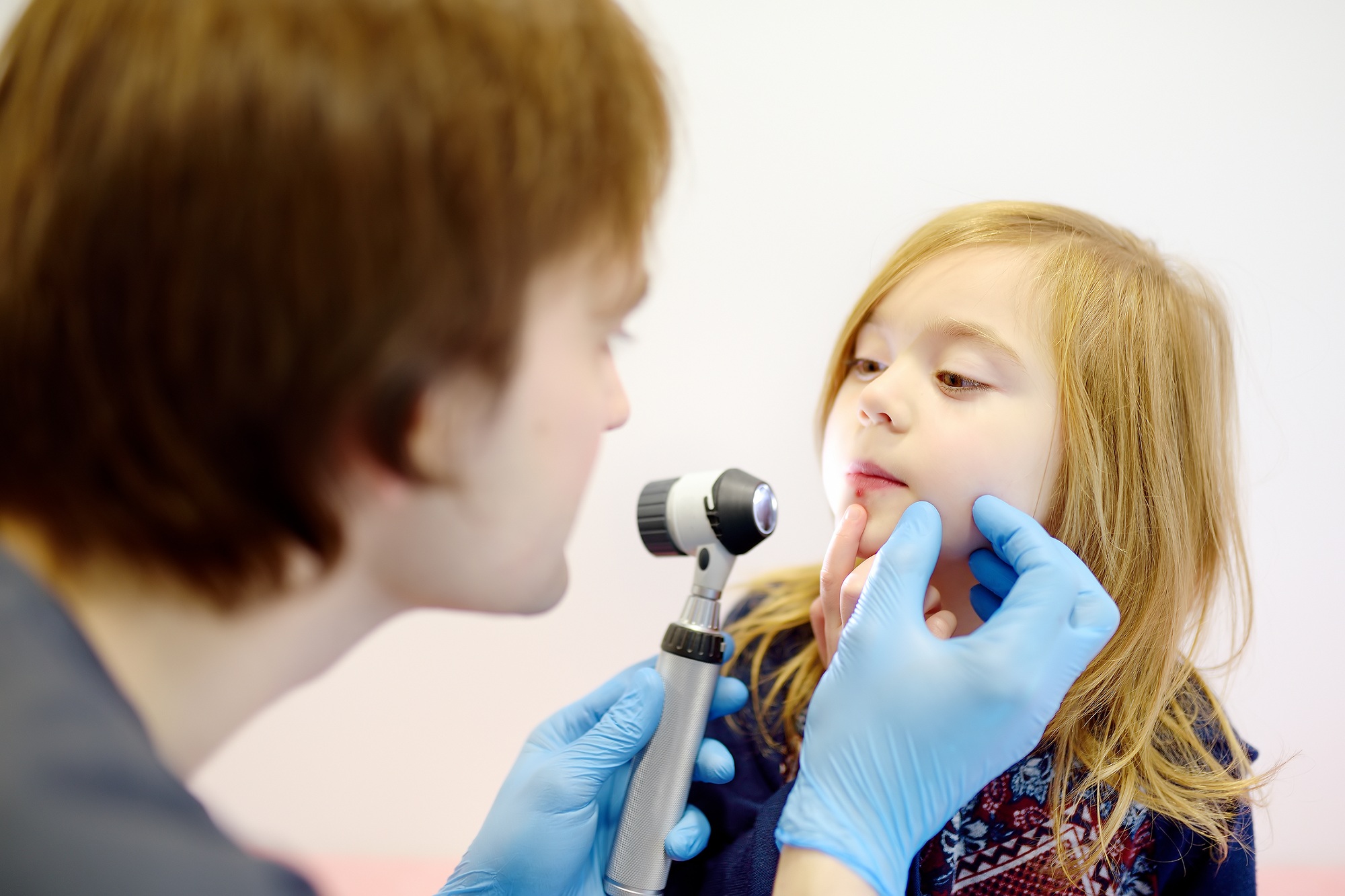 Cute little girl during appointment of dermatologist in modern clinic.