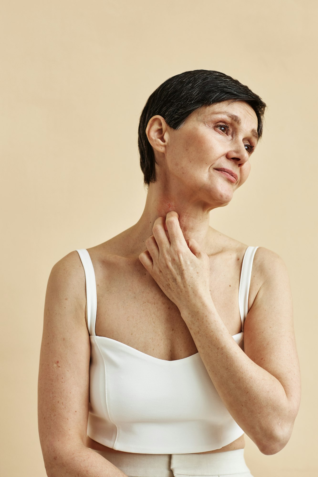 Minimal mature woman scratching neck with psoriasis spot skin condition