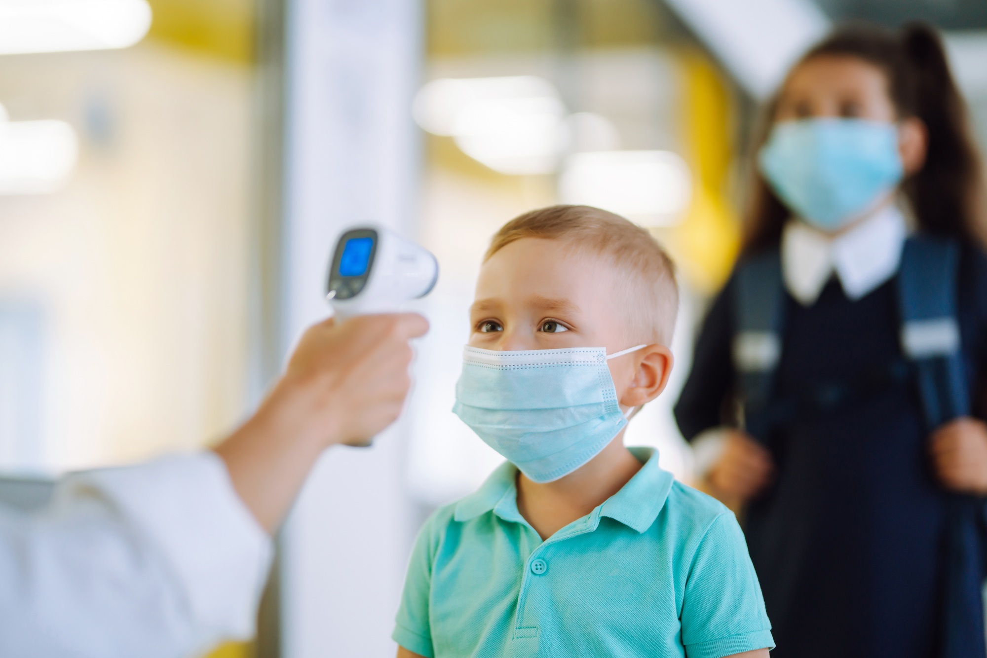 Nurse or doctor checks children body temperature using infrared forehead thermometer for virus.