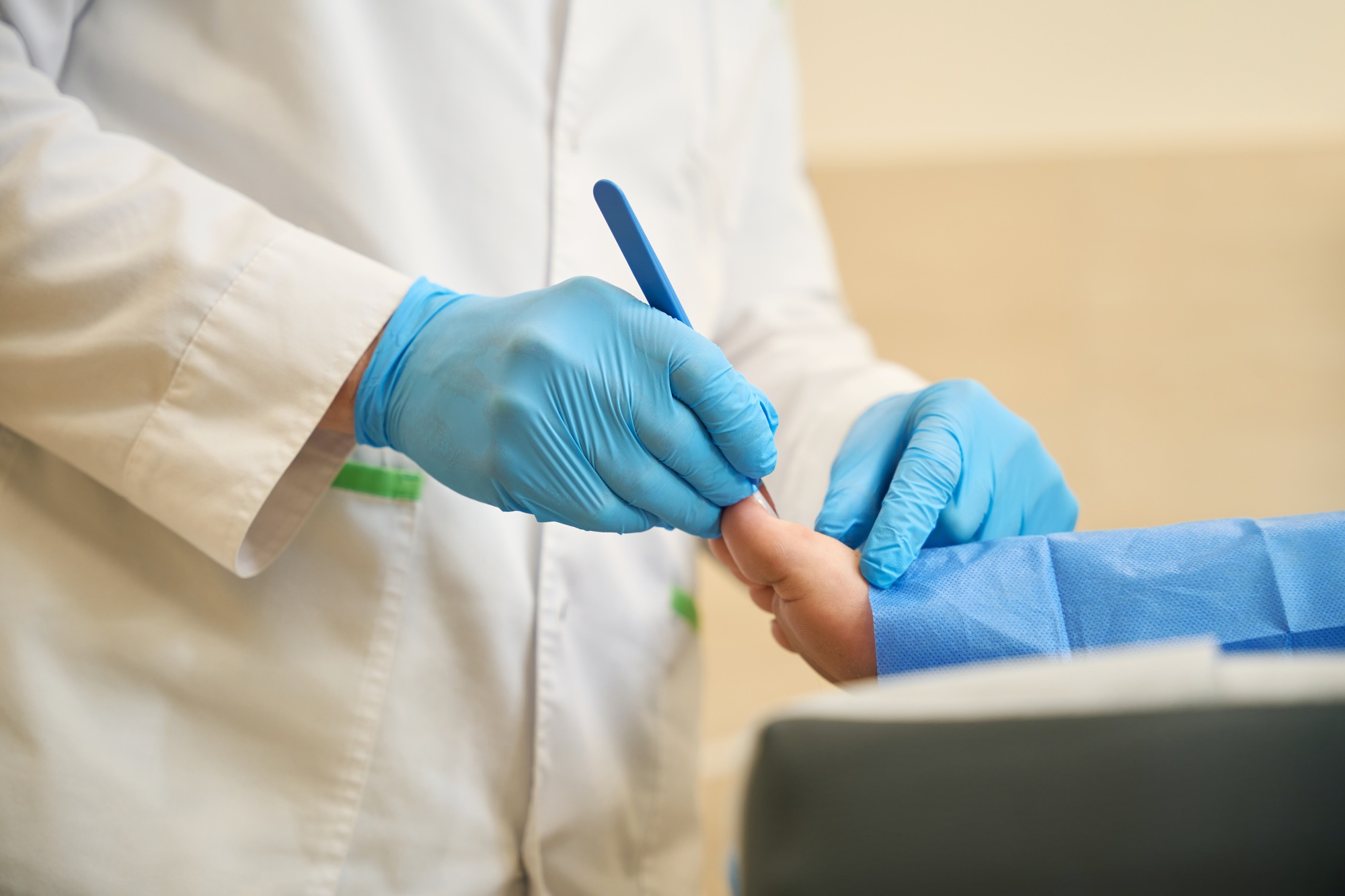 Podiatrist performing toenail surgery on adult person