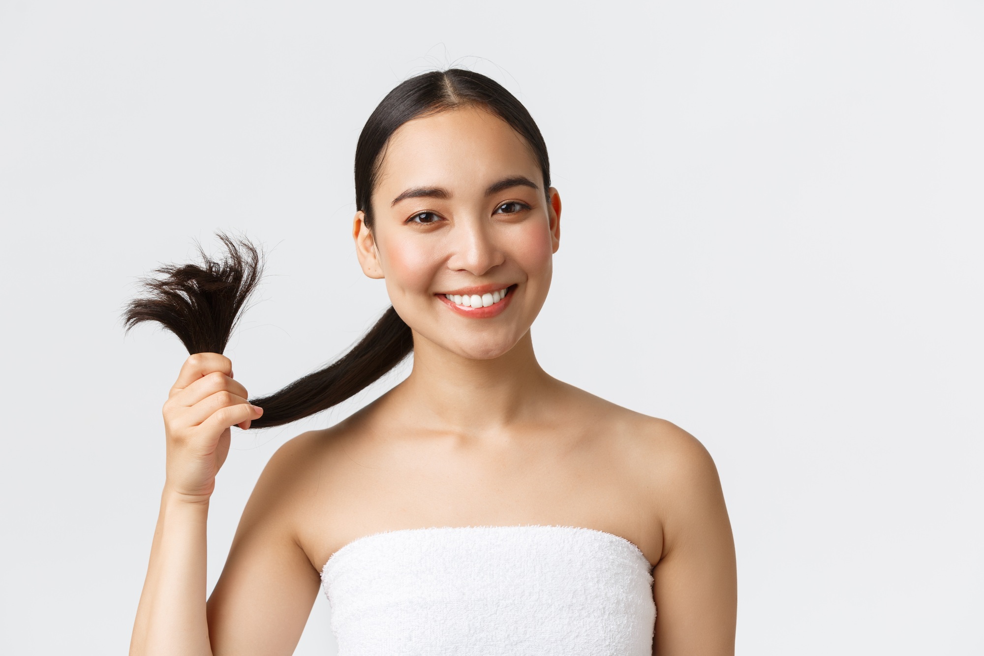 Beauty, hair loss products and hair care concept. Happy gorgeous asian girl in bath towel showing