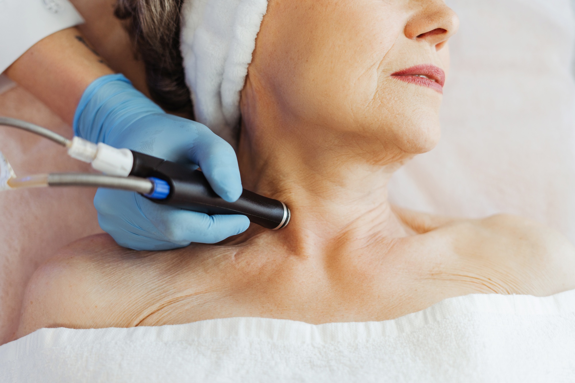 Closeup doctor cosmetologist doing cosmetic procedures, hydro facial on neck of older, elderly woman