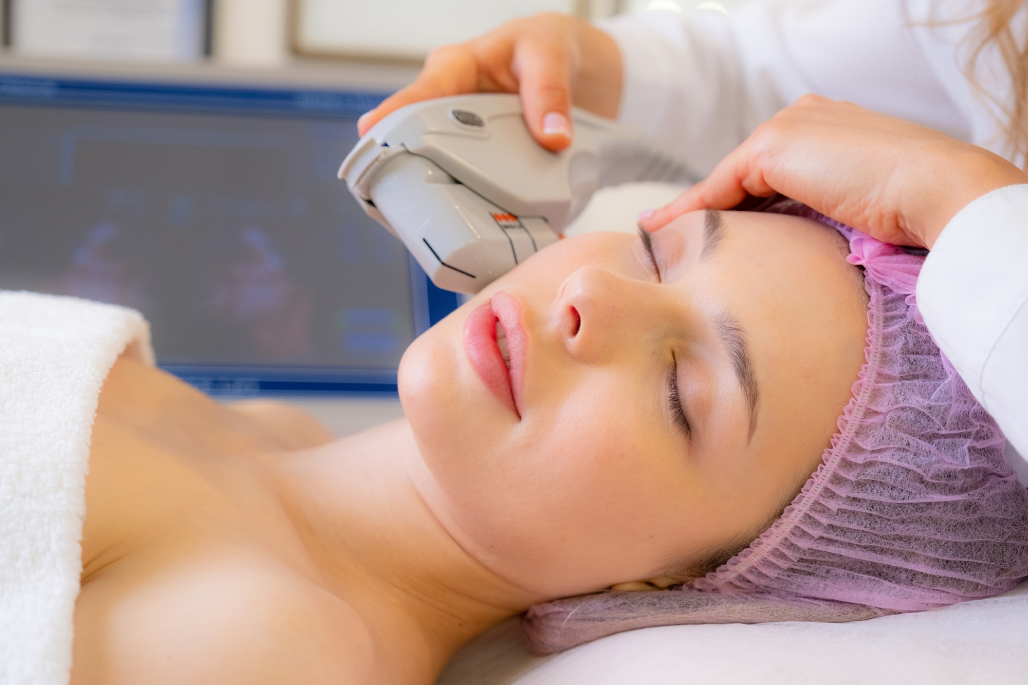 Cosmetologist making a woman a therapeutic laser processing on a face