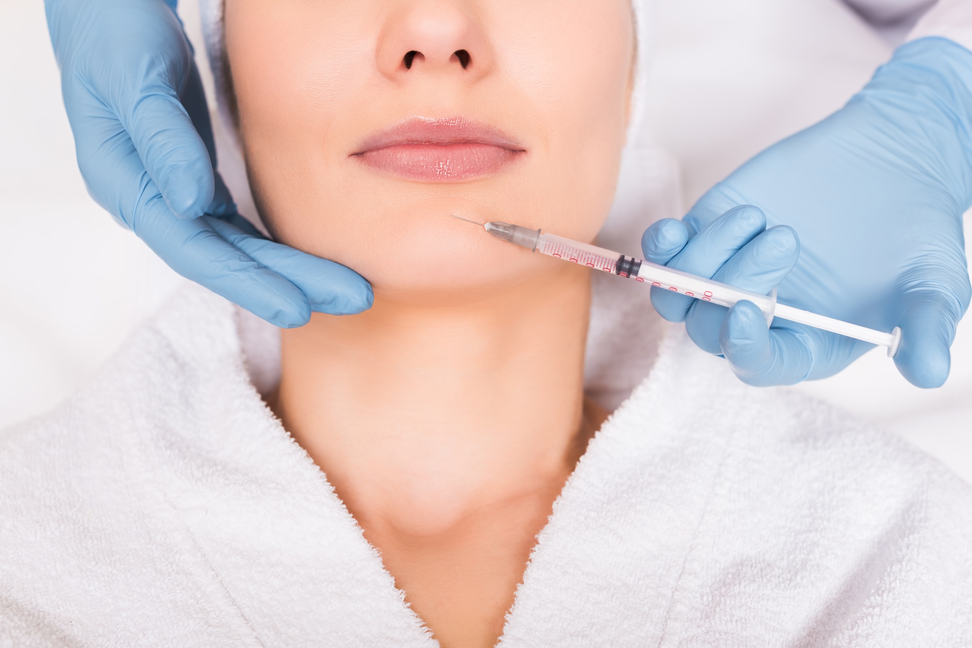 cropped view of beautician injecting face woman at beauty salon