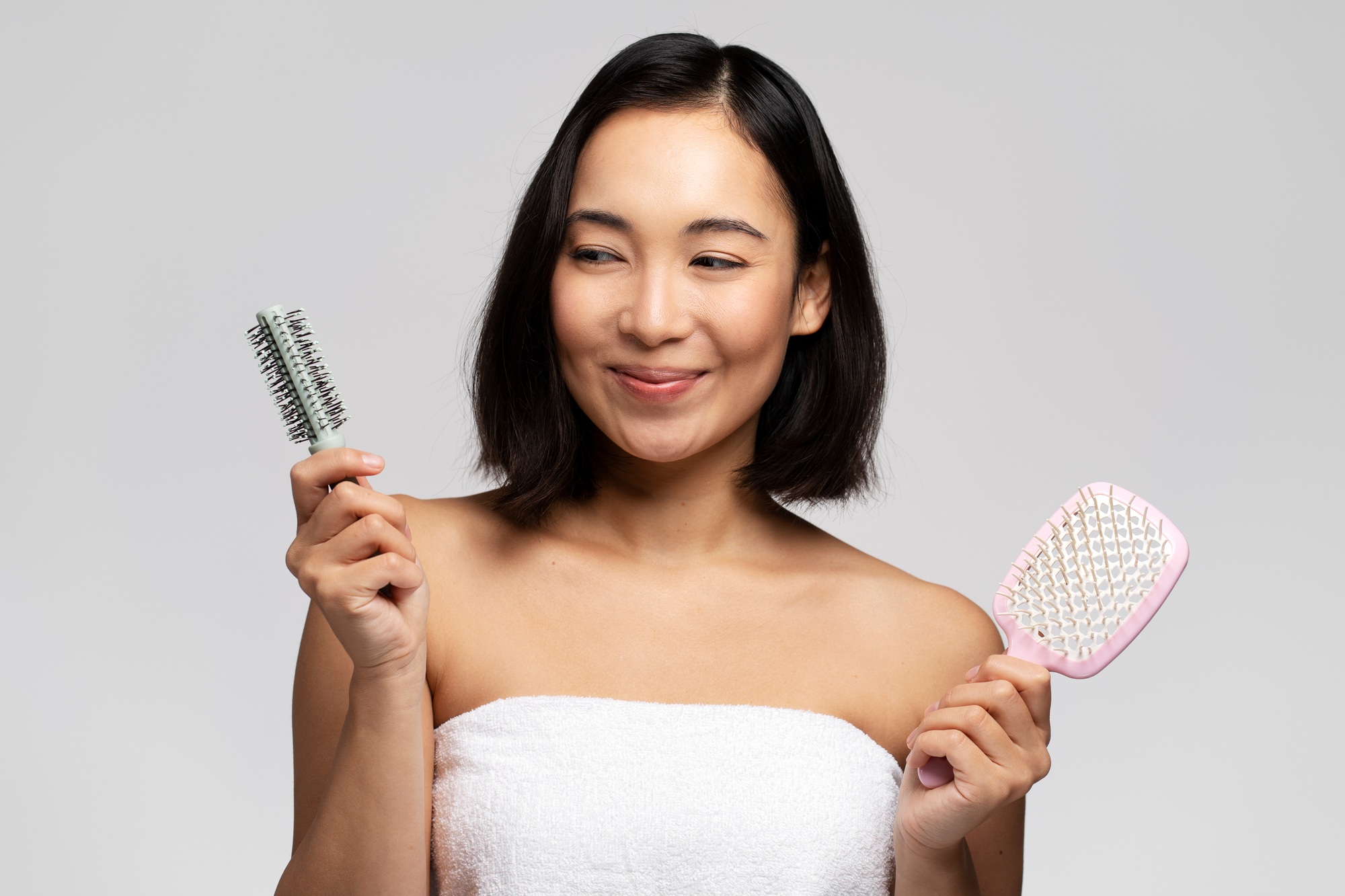 Hair treatment. Portrait of positive brunette woman holding two hair brushes