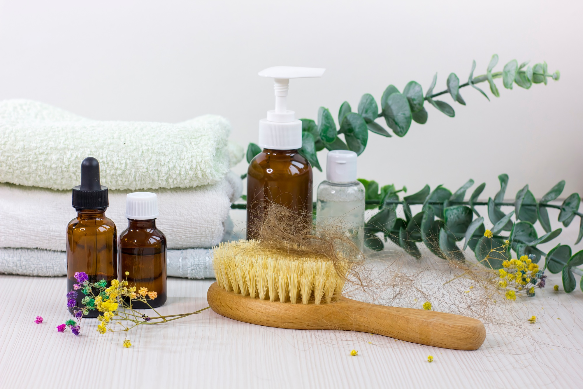 Medication bottles, hairbrush and towel on white wooden table. Hair loss problem.