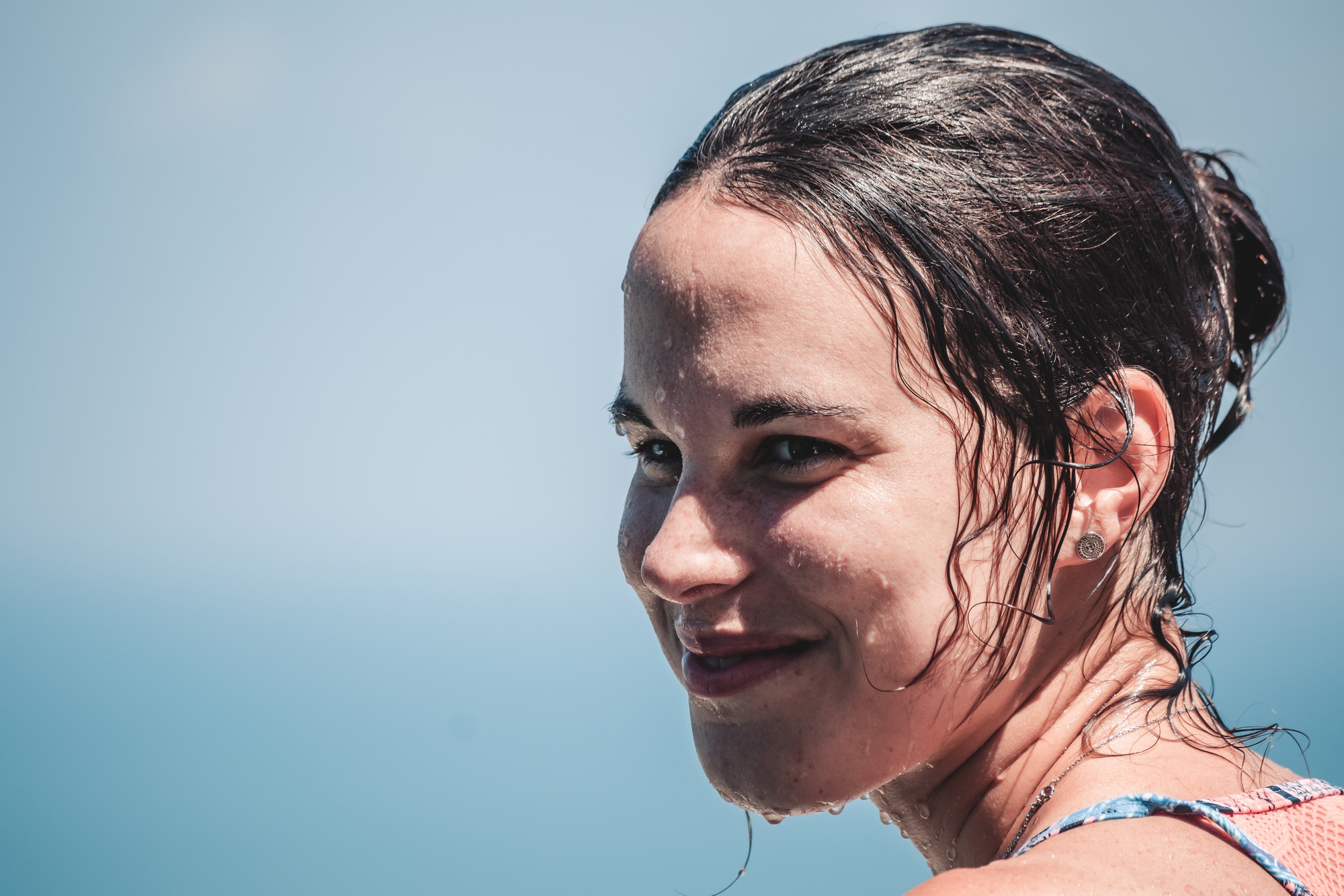 Portrait of a young woman, smiling, with her face wet from the sea water.