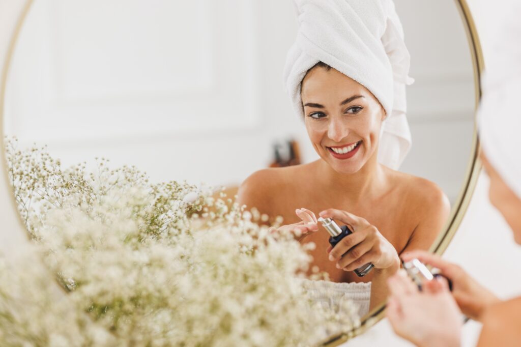 Woman In Front Of Mirror Applying Moisturizer On Her Face At The Beauty Salon