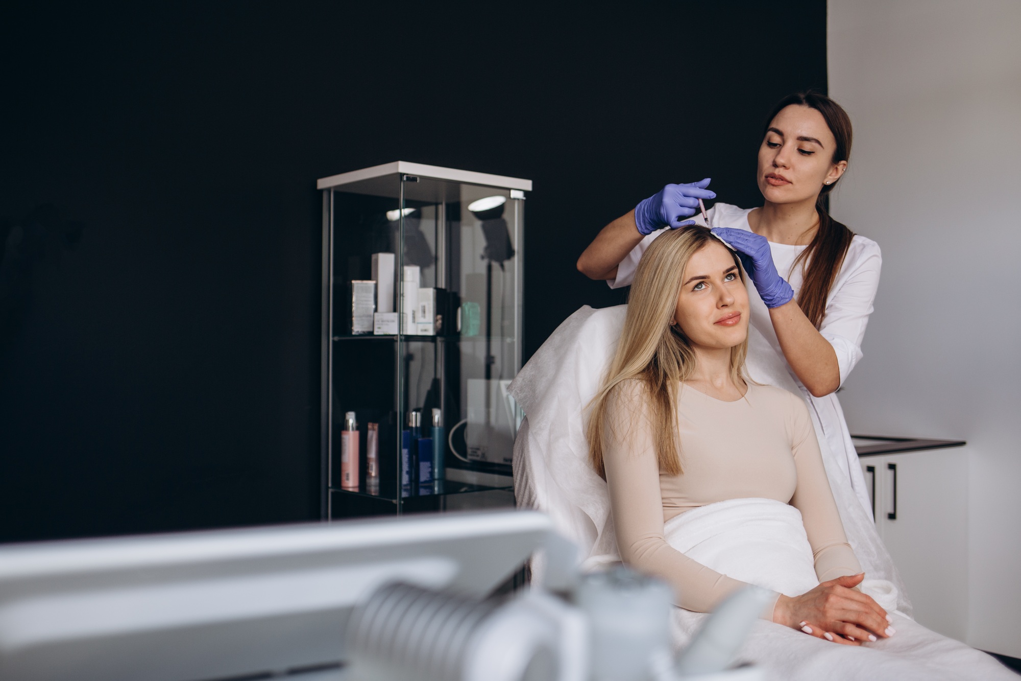 Young woman with hair loss problem receiving injection in salon