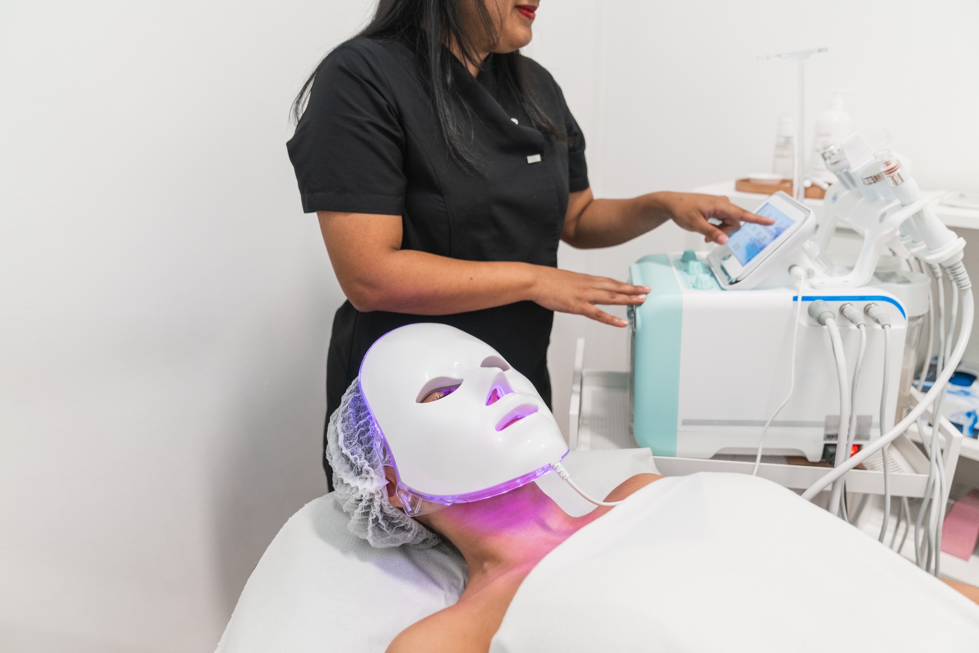 Beautician preparing led light therapy facial treatment for woman