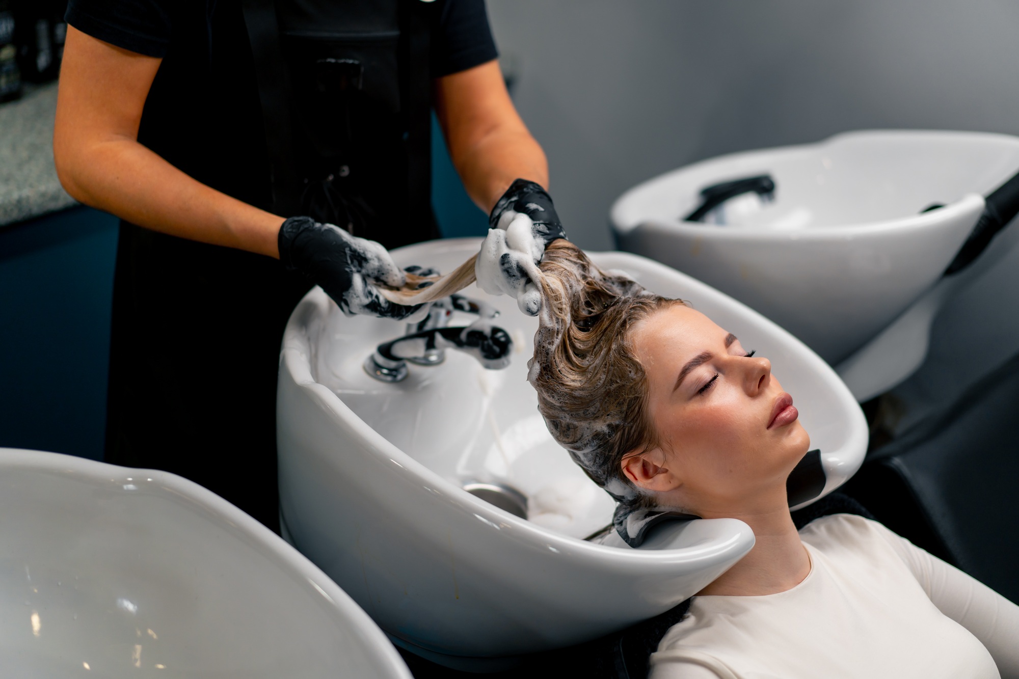 close-up of a hairdresser washing off dye from a client's hair during a care procedure in a salon