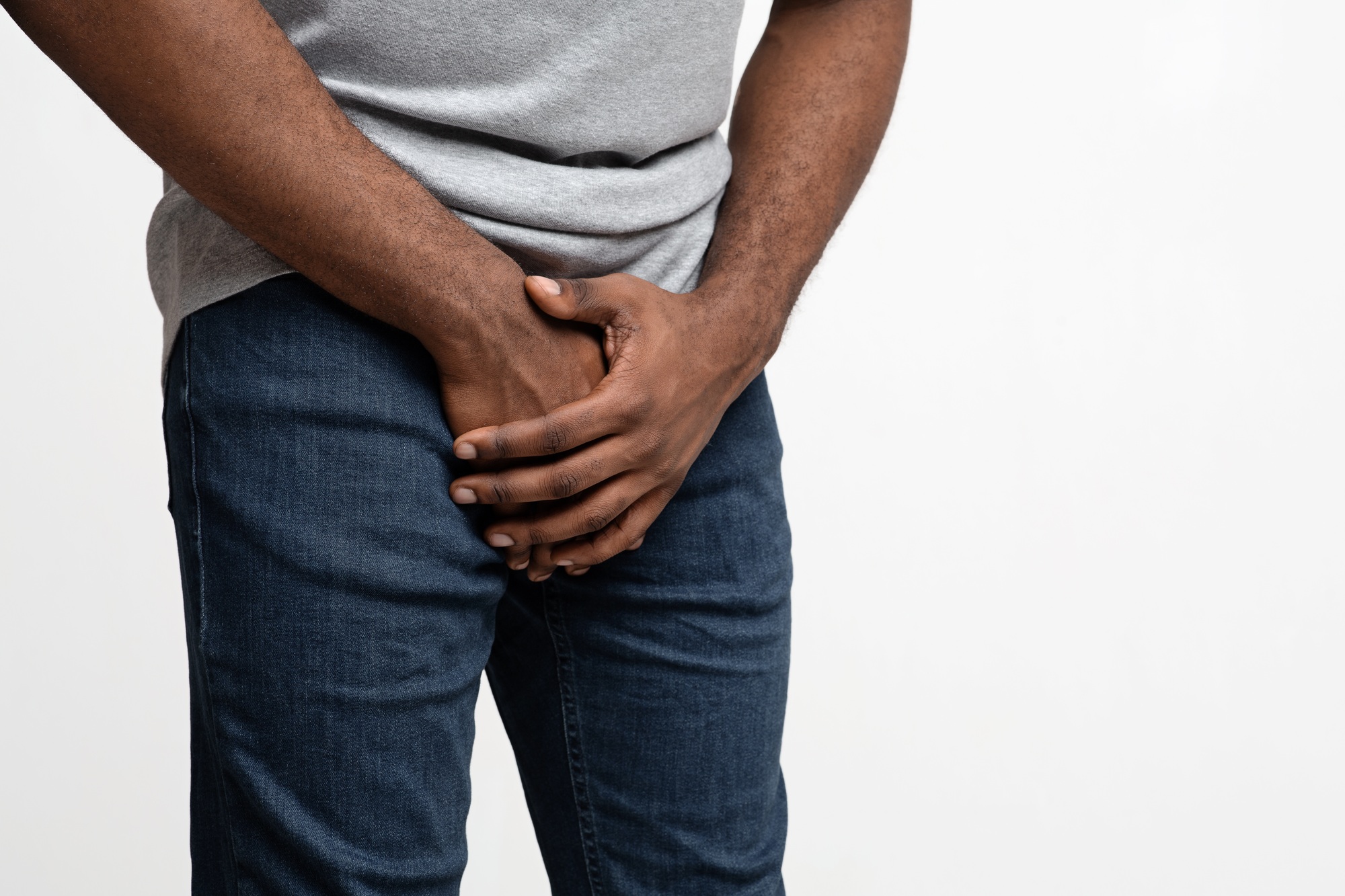 Cropped of black guy holding his groin