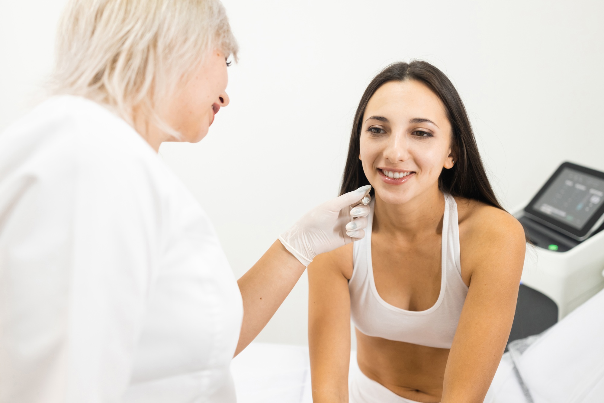 Doctor cosmetologist examines the skin on the patient's face