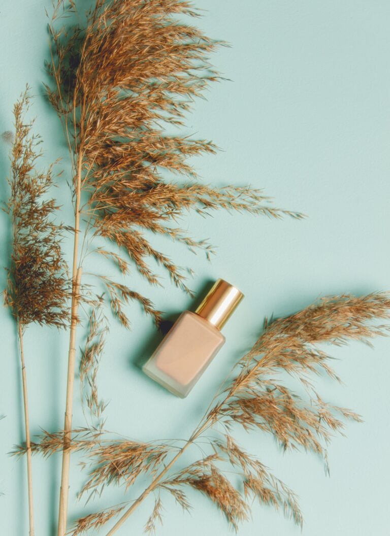 Dry bulrush and nail polish on blue background.