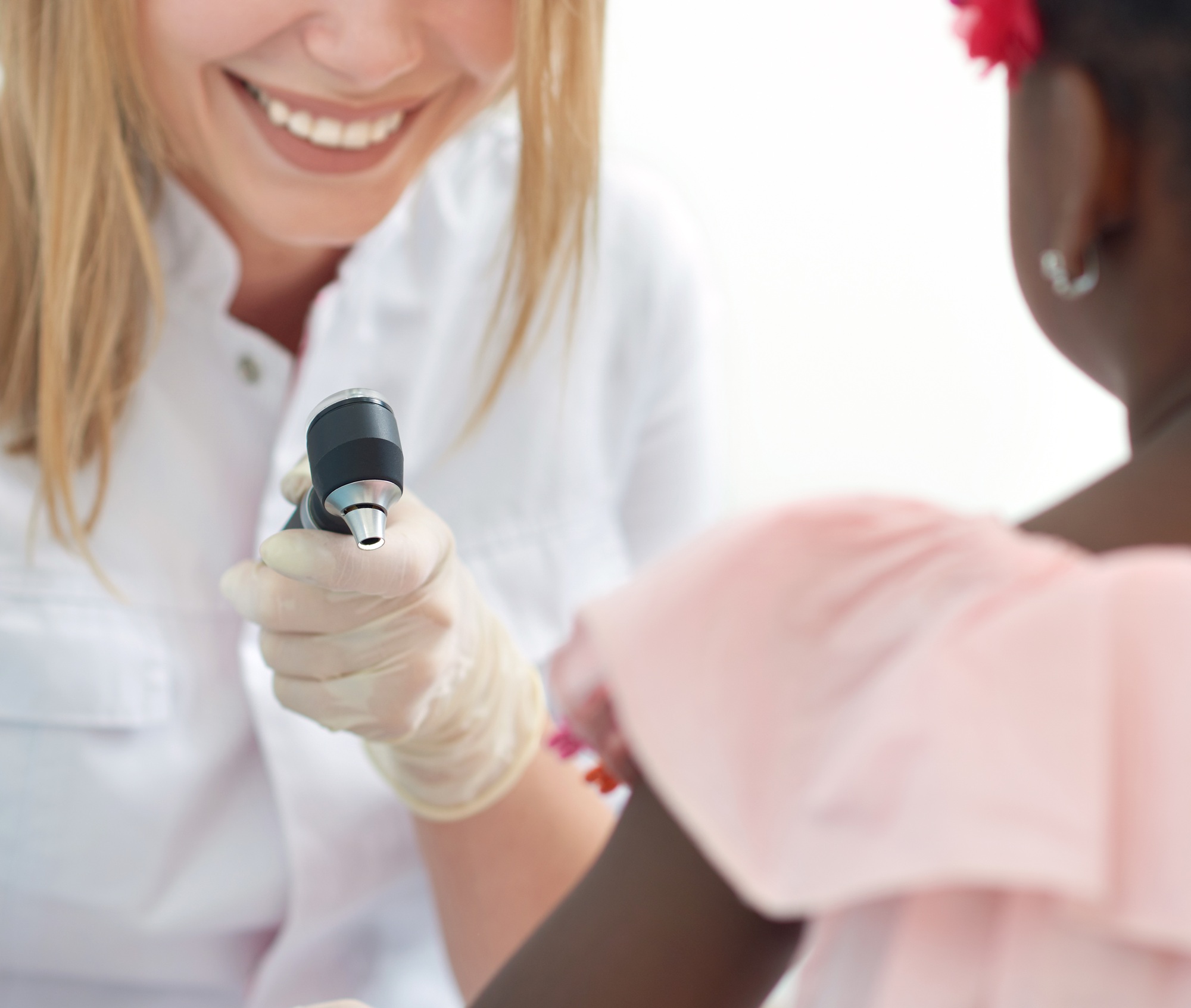 Female doctor checking skin of afro child with dermatoscope