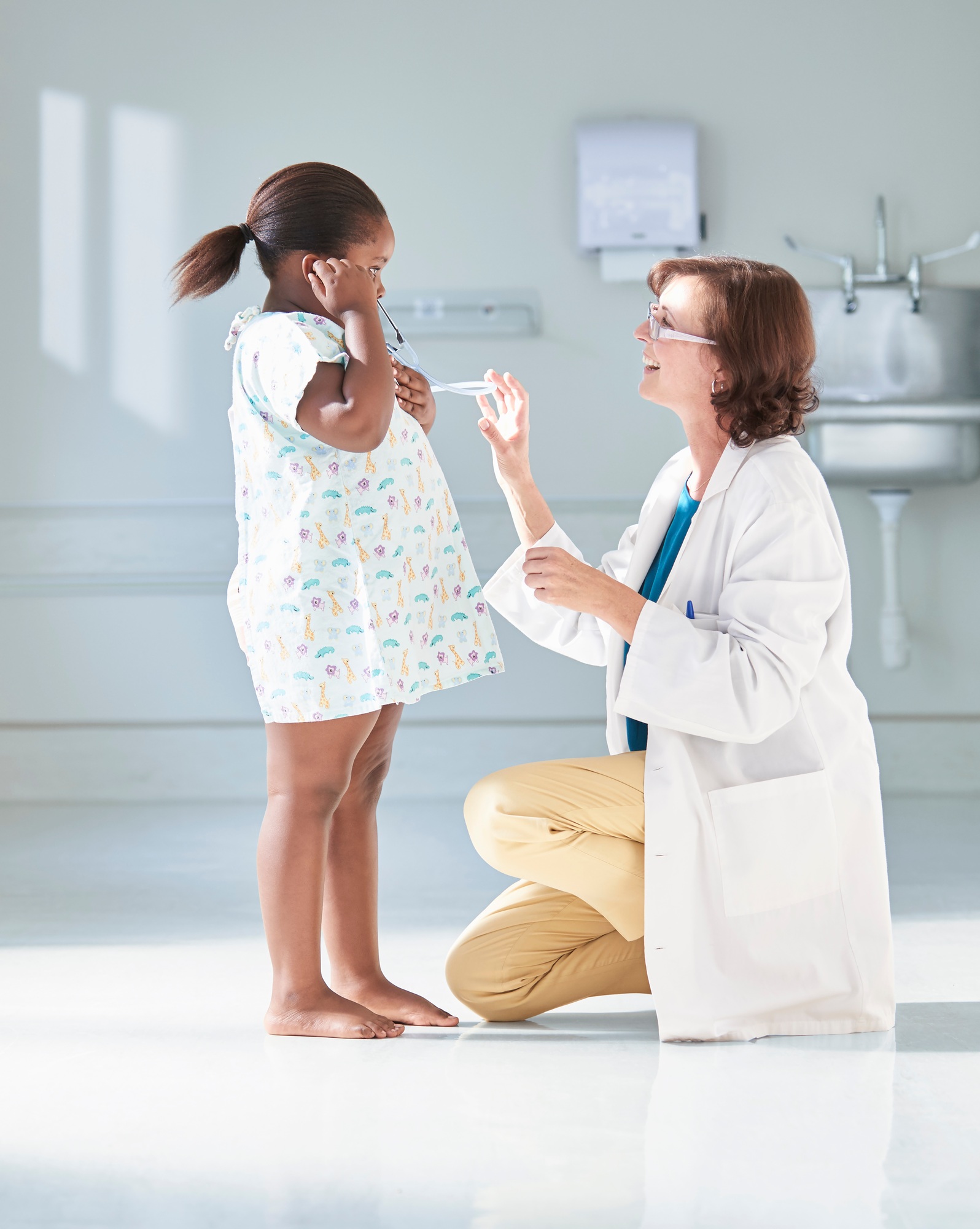 Girl listening to doctors stethoscope in hospital children's ward