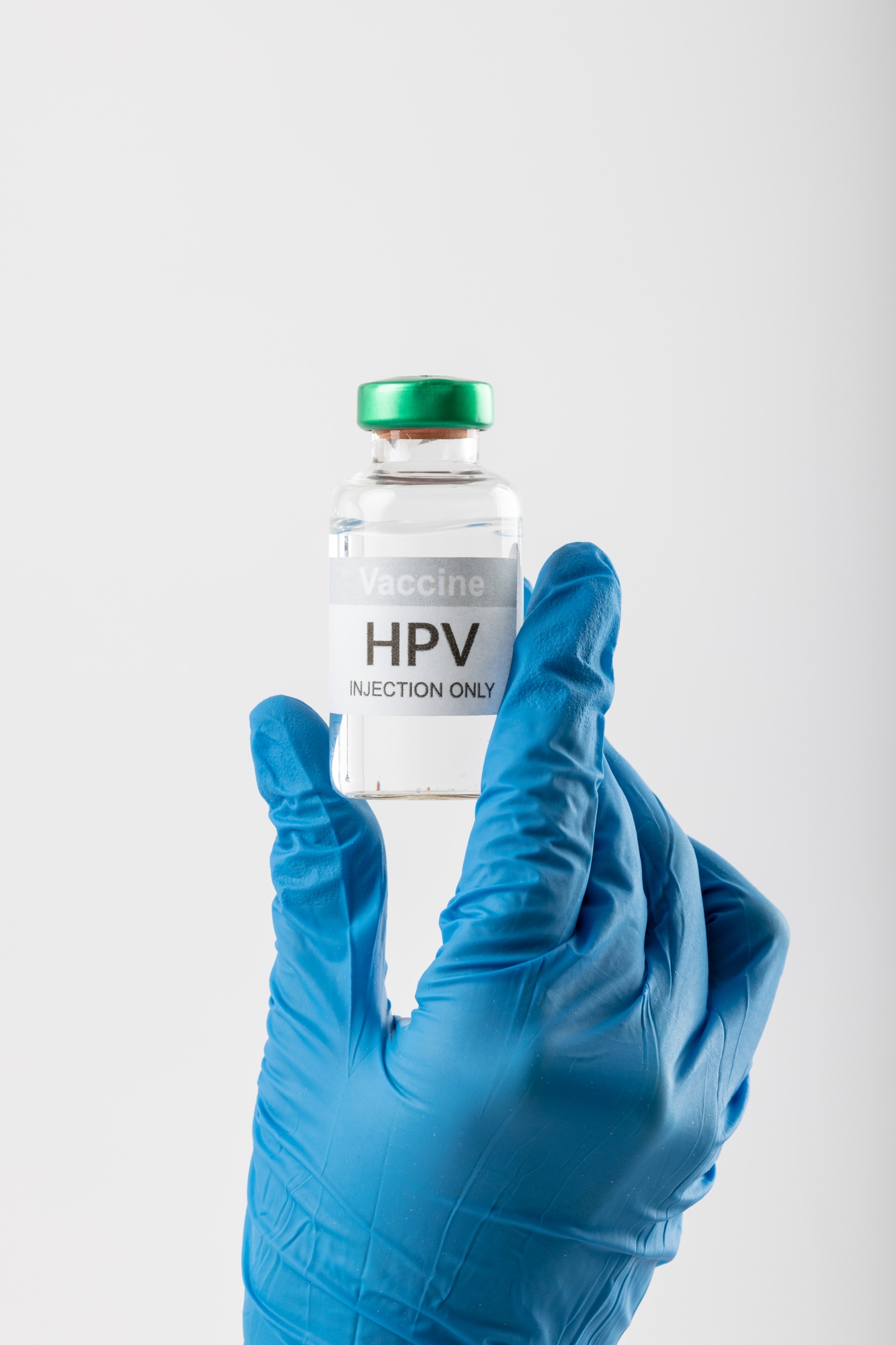 Vertical of doctor's gloved hand holding hpv vaccine vial on white background with copy space