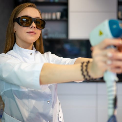 Female cosmetologist with a laser for hair removal