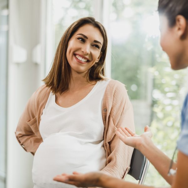 Pregnant Woman Talking To Gynecology Nurse At Waiting Room