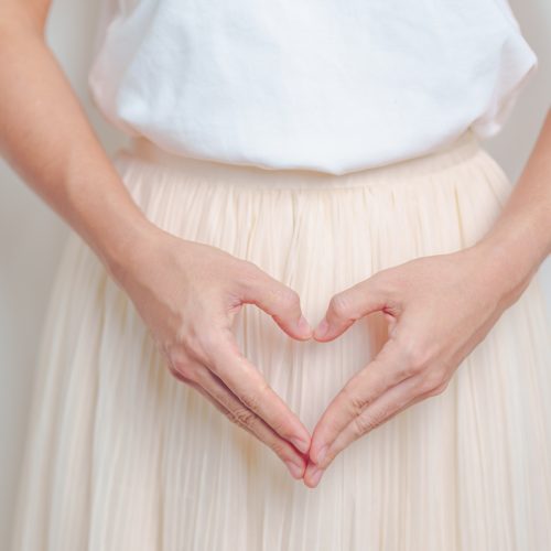 Woman hand heart shape over abdomen. Ovarian and Sexual Transmitted disease concept