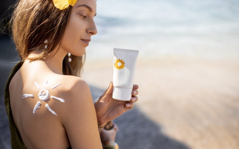 Woman with sunscreen lotion on the beach